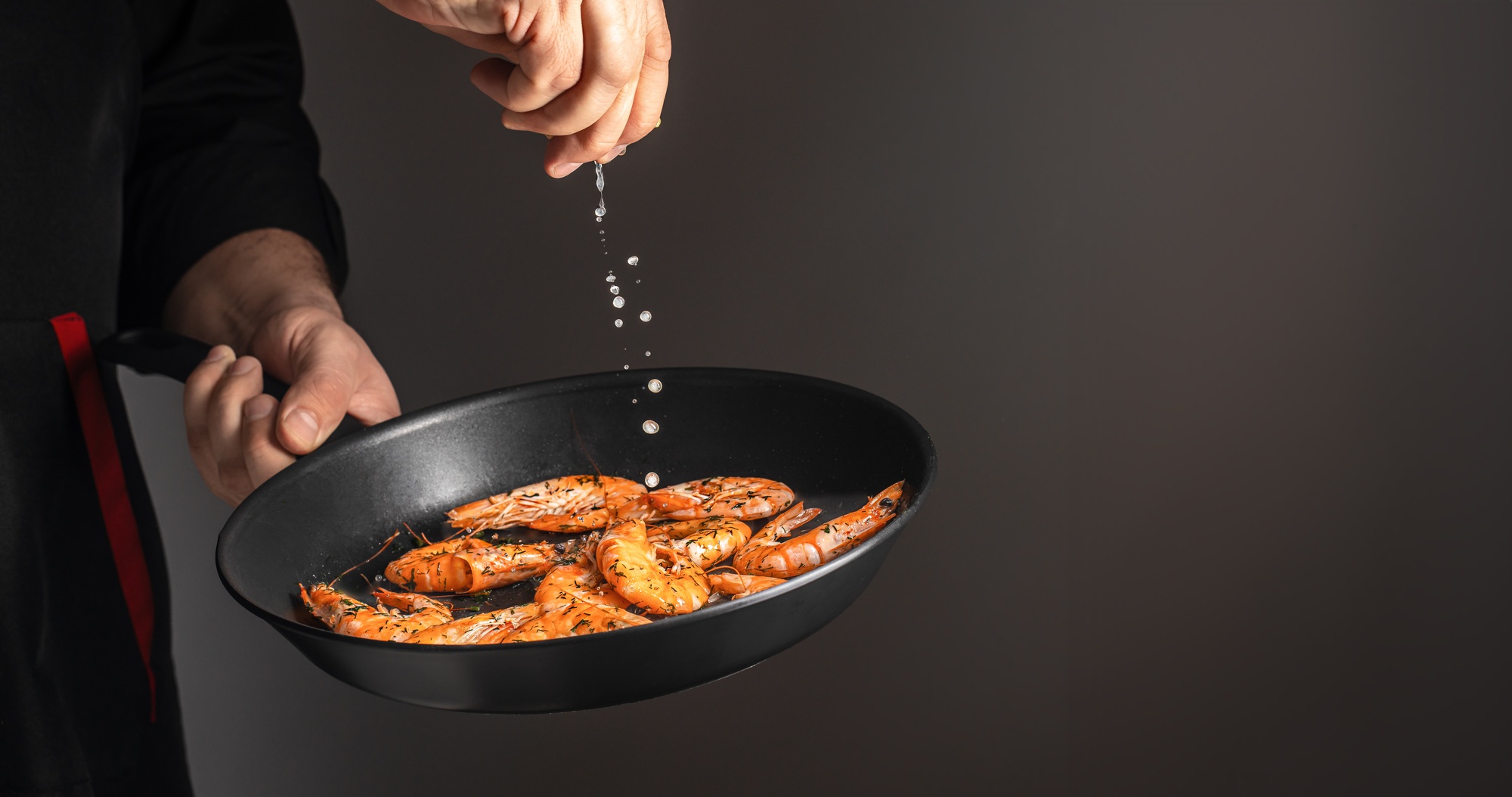 Professional chef cooked shrimp seafood in pan on a dark background. copy space